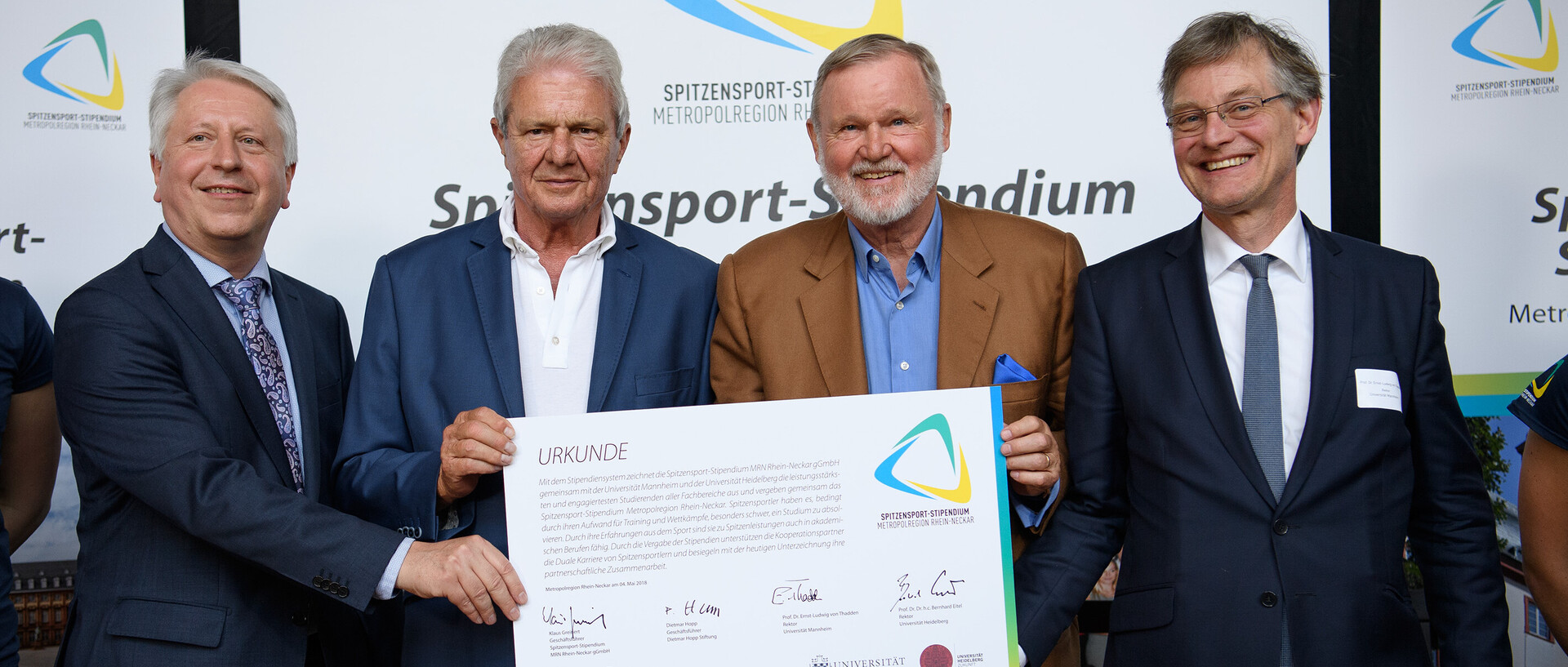 Vier Männer posieren mit einer Urkunde des Spitzensport-Stipendiums.
