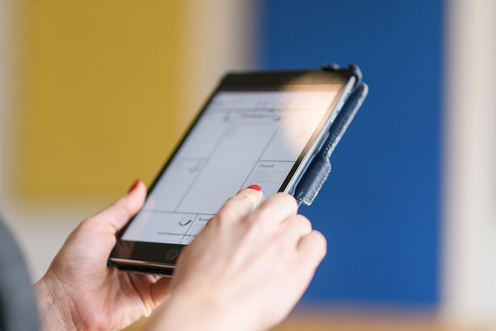 Hände halten ein Tablet fest.