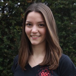 Felicia Bischoff has long brown hair. She is wearing a black T-shirt with the University of Mannheim logo and the print of the departmental student committee for Language and Literature.