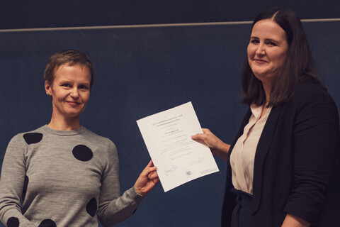 Mona Wenisch wird von Professorin Cornelia Ruhe ein Preis für ihre wissenschaftliche Arbeit übergeben.