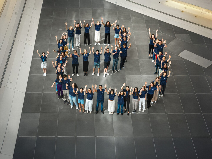 Um die 40 Studierende mit blauem T-Shirt bilden den Buchstaben e. Das Ende des e ist so geformt, dass es auch als u gelesen werden kann, also als "eu". Link: Europäische Universität ENGAGE.EU