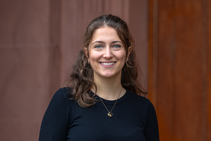 Annika lächelt freundlich in die Kamera. Sie hat lockige, braune Haare und trägt ein schwares Oberteil.