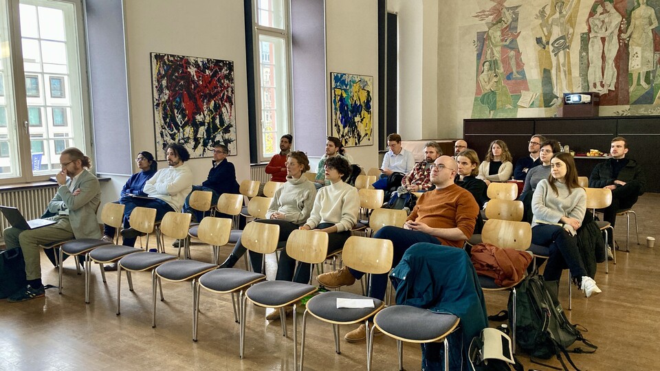 The 25 or so speed dating participants sit in rows of chairs in the Fuchs Festsaal