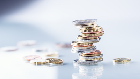 Münzgeld verschiedenen Wertes liegt aufeinander gestapelt auf einem Tisch.