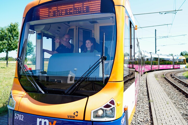 Blick von außen in den Führerstand der Straßenbahn, in der ein Mitarbeiter der rnv Marleen Quurk etwas erklärt. 