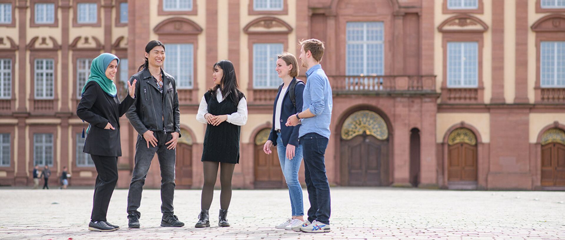 A group of doctoral students is standing on the Ehrenhof in front of the castle.