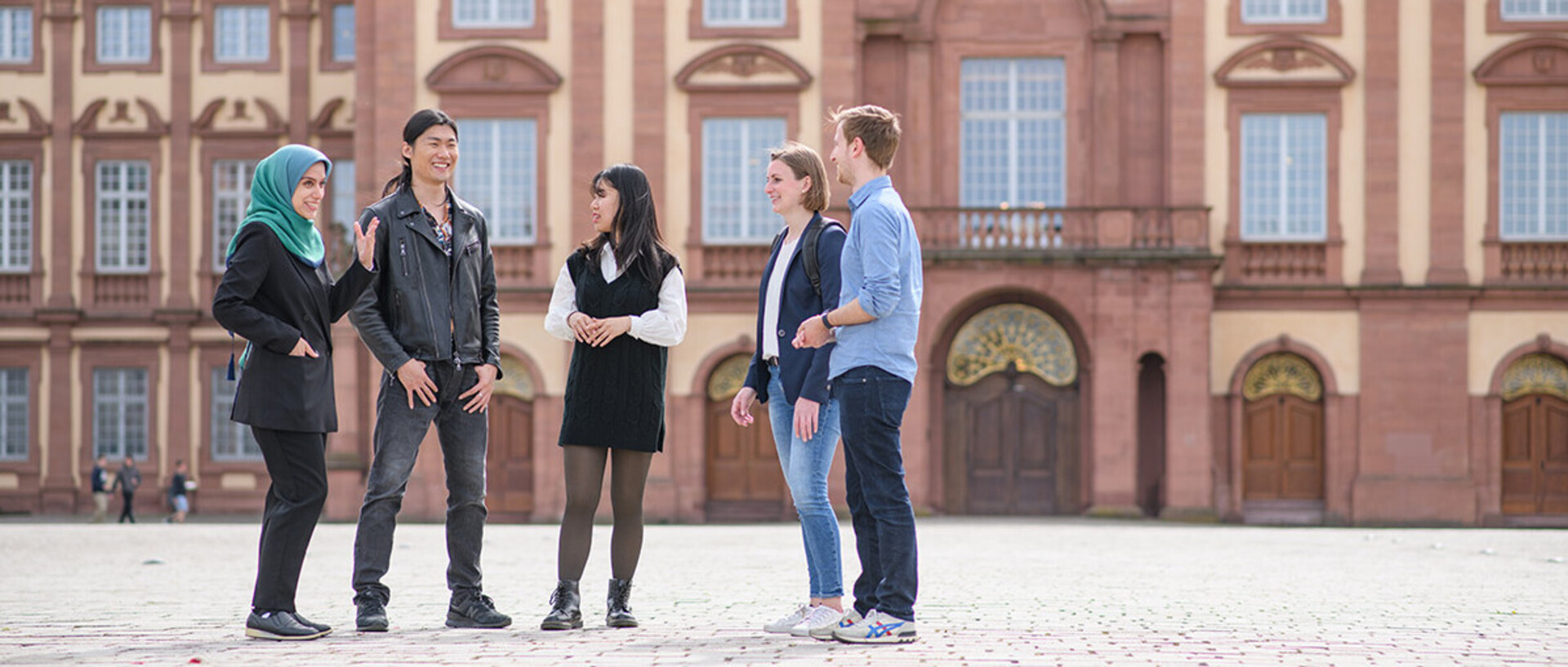 A group of students are talking on the Ehrenhof in front of the castle.