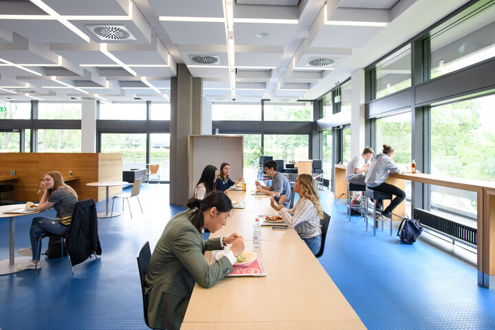 Studierende sitzen in der Mensa und essen. 