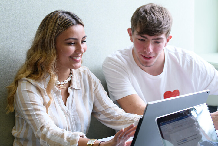 zwei Studierende betrachten gemeinsam einen Laptop.