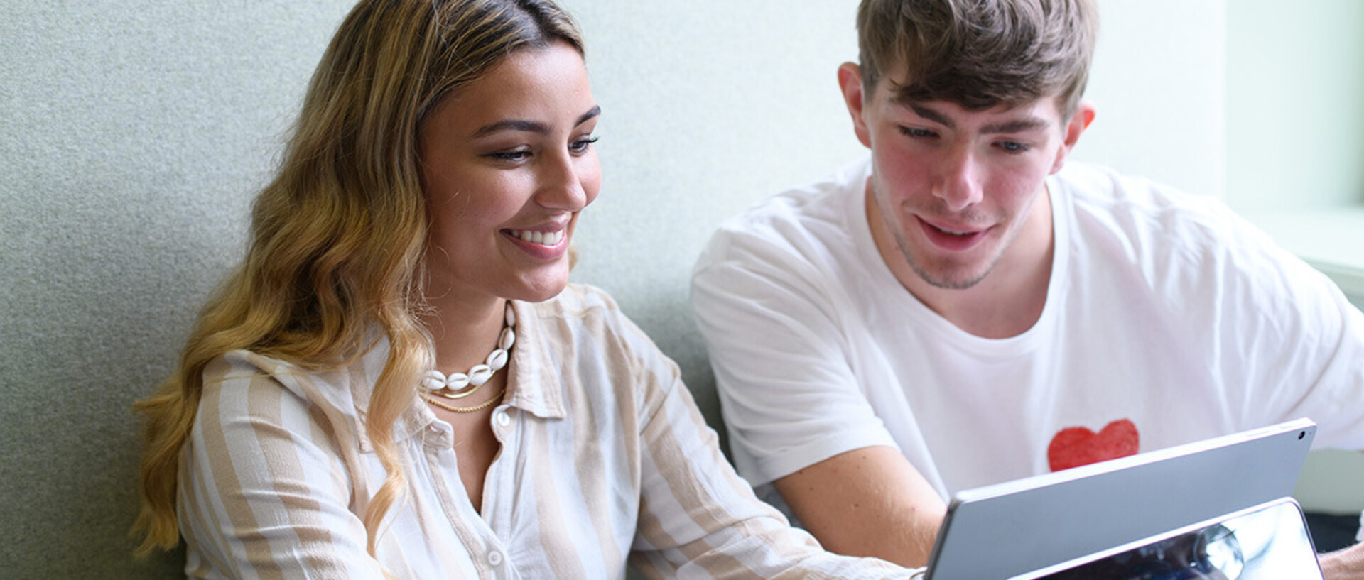 zwei Studierende betrachten gemeinsam einen Laptop. 
