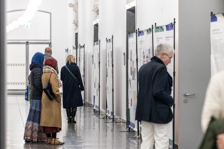 Viele Personen stehen im Flur der Universität Mannheim und schauen sich Ausstellungstafeln einer Vernissage an.