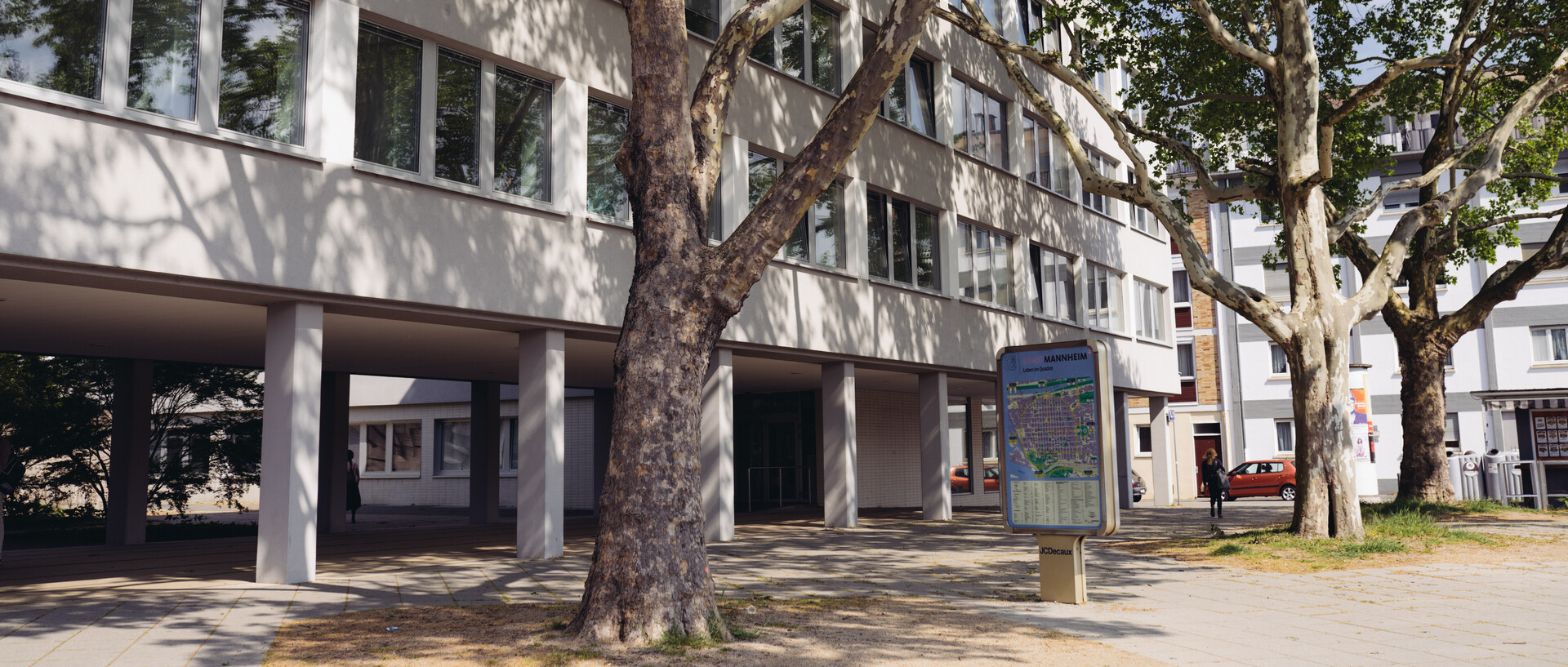 Gebäude von L1 bei sonnigem Wetter und mit Bäumen davor
