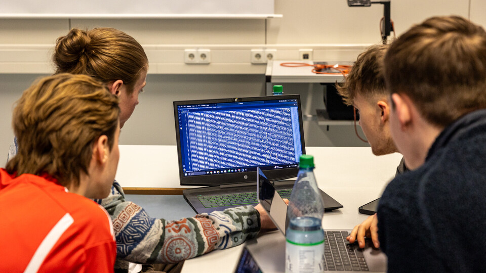 Arbeitsgruppe schaut auf Laptop-Bildschirm