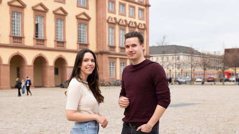 Zwei lächelnde Personen stehen sich auf dem Ehrenhof gegenüber. Die Personen heißen Melina und Sandro.