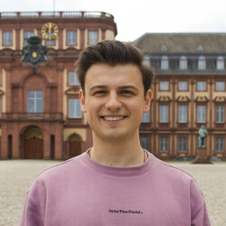 Philipp steht auf dem Ehrenhof des Schlosses und lächelt freundlich in die Kamera.