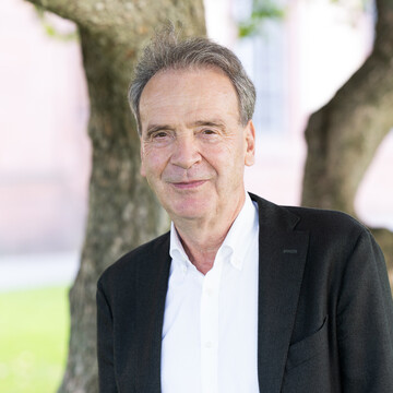  Prof. Stefan Reichelstein. Er lächelt und trägt einen schwarzen Anzug.