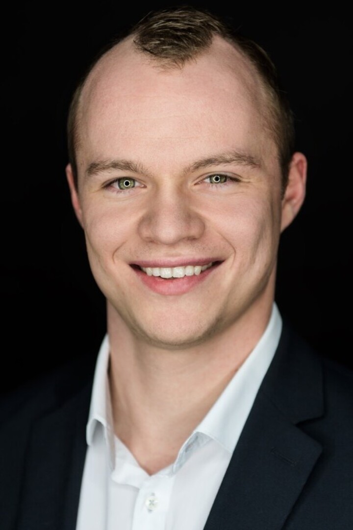 André Dörrzapf hat grüne Augen und trägt ein weißes Hemd mit schwarzem Sakko