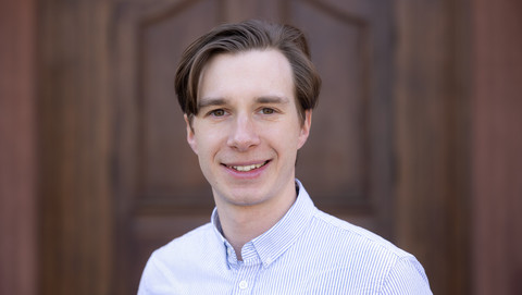 Hannes Twieling. He is wearing a white shirt and is standing in front of a brown door.