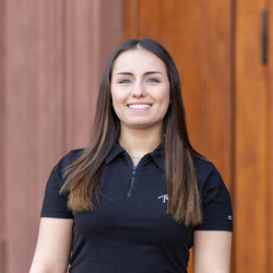 Sinem has straight, dark brown hair and is wearing a black T-shirt. She is smiling at the camera.