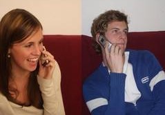 Ein zweigeteiltes Bild, das eine Frau und einen Mann zeigt, die jeweils auf einem roten Sofa sitzen und telefonieren.