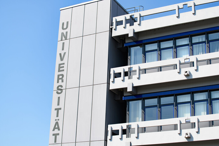 Die oberen Stockwerke eines Universitätsgebäudes mit der vertikalen Aufschrift Universität.