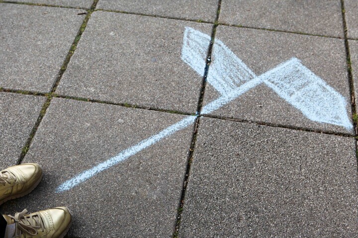 Zwei blaue Pfeile aus Kreide auf Steinplatten. Sie zeigen in entgegengesetzte Richtungen.