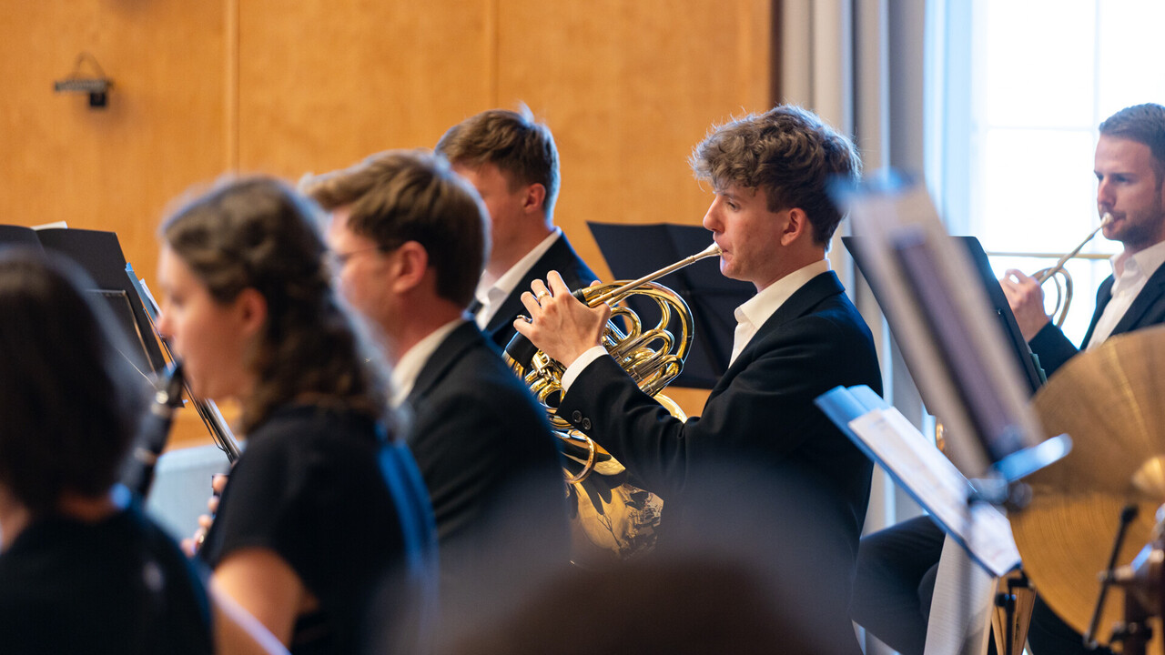 Auftritt des Unichorchesters. Studierende sind schwarz gekleidet und spielen jeweils ein Instrument.