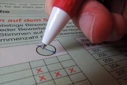 Eine Person macht auf einem Wahlschein ein Kreuz.
