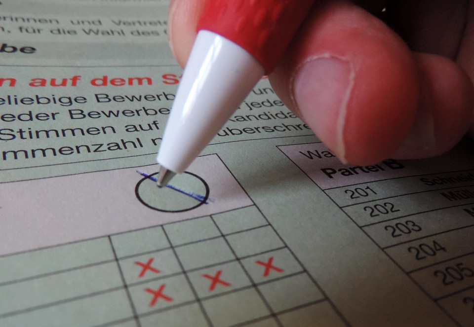 Eine Person macht auf einem Wahlschein ein Kreuz.