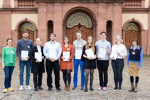 Lehr­ende, Mitarbeitenden und Studierende stehen mit ihren Zertifikaten zur Hochschuldidaktik auf dem Ehrenhof.