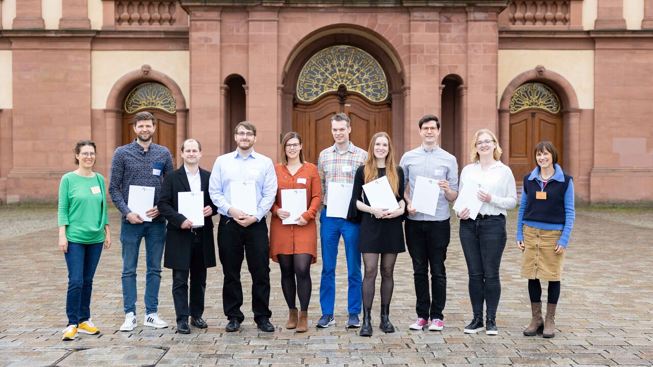 Lehr­ende, Mitarbeitenden und Studierende stehen mit ihren Zertifikaten zur Hochschuldidaktik auf dem Ehrenhof.