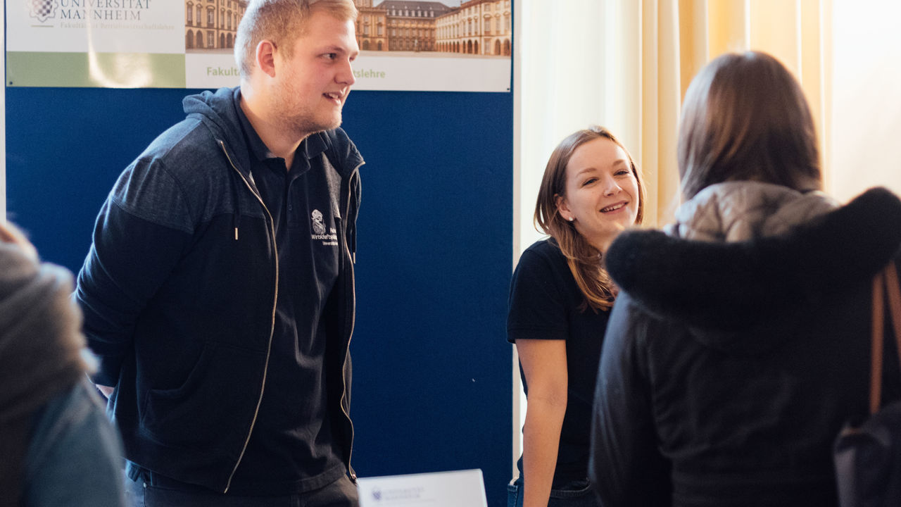 Mitarbeitende der Uni Mannheim informieren an einem Stand beim Studieninformationstag