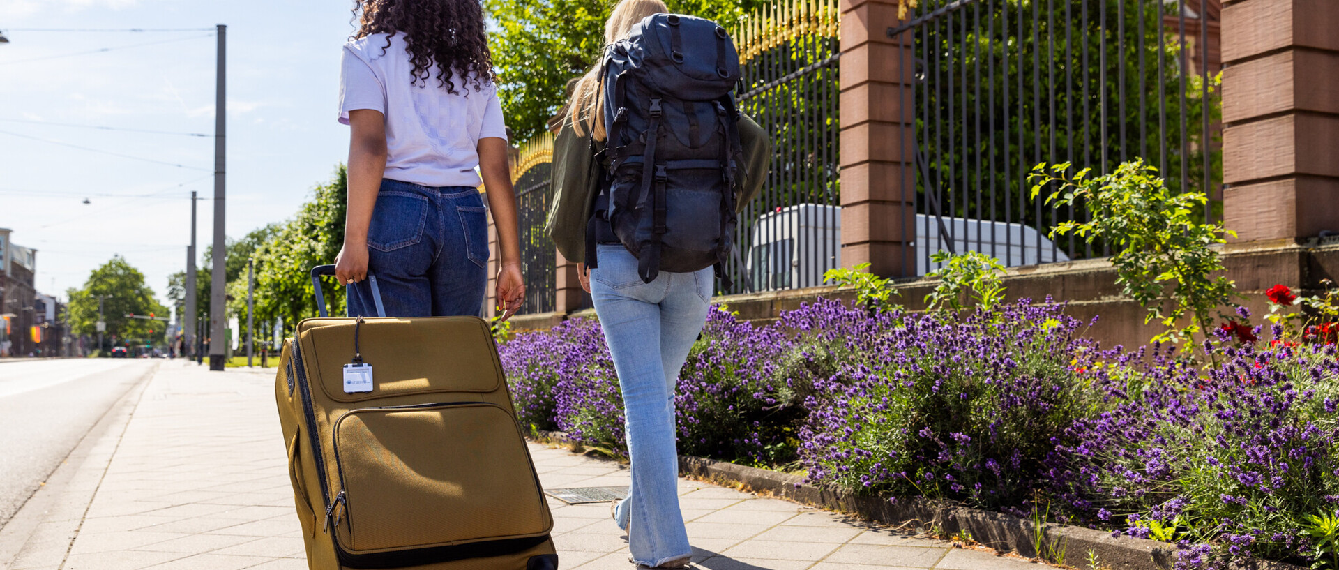 Zwei Studierende mit einem Koffer und Reiserucksack vor dem Mannheimer Schloss.