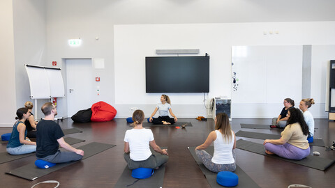 Eine Gruppe von Mitarbeitenden bei einer Yogastunde in der Uni