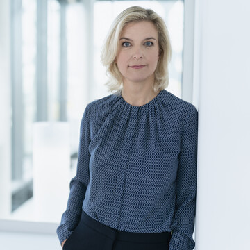 Nina Schwab-Hautzinger hat kurze blonde Haare. Sie trägt eine dunkelblaue Bluse
