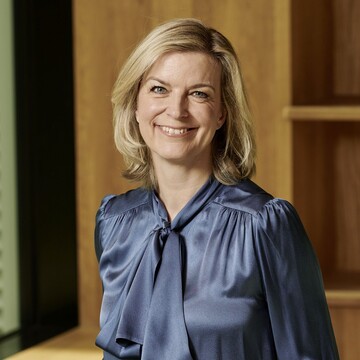 Nina Schwab-Hautzinger hat kurze blonde Haare. Sie trägt eine dunkelblaue Bluse