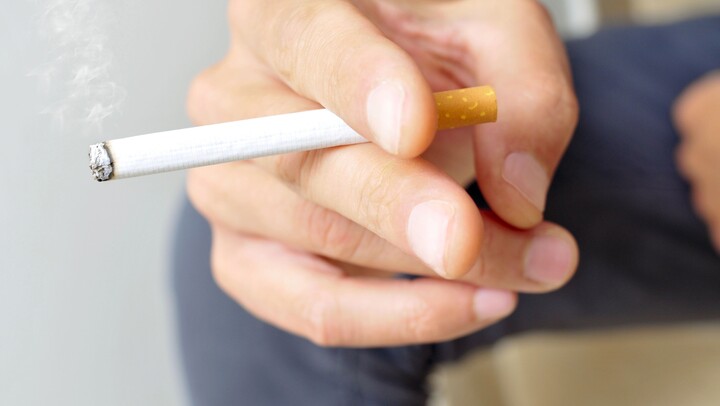 Großaufnahme einer Hand mit einer brennenden Zigarette