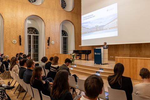 Viele Menschen hören einer vortragenden Person zu