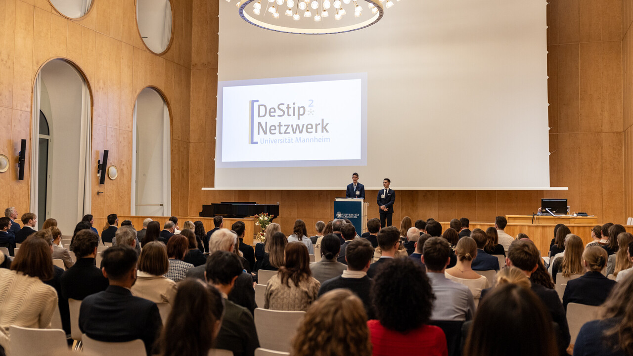 Die Gäste der Feier sitzen in der Aula während vorne eine Rede gehalten wird