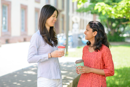 Zwei Frauen mit Kaffebechern unterhalten sich.