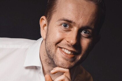 Moritz Ingendahl dressed in white shirt in front of dark background