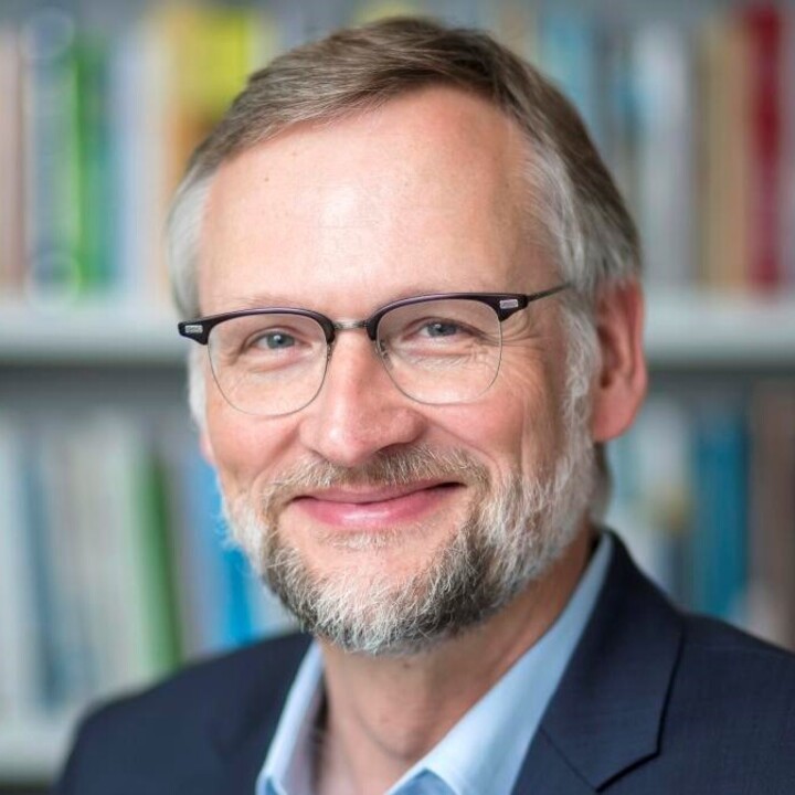 Foto  Prof. Dr. Ralph Hertwig; er trägt eine Brille, einen blauen Anzug und einen Bart