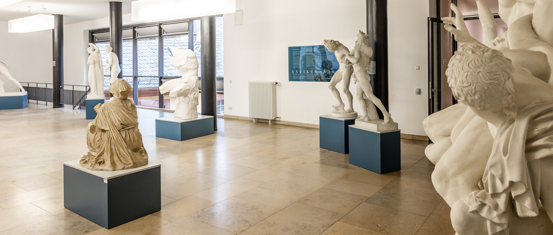 In einem Gang sind antike Skulpturen von Menschen ausgestellt.