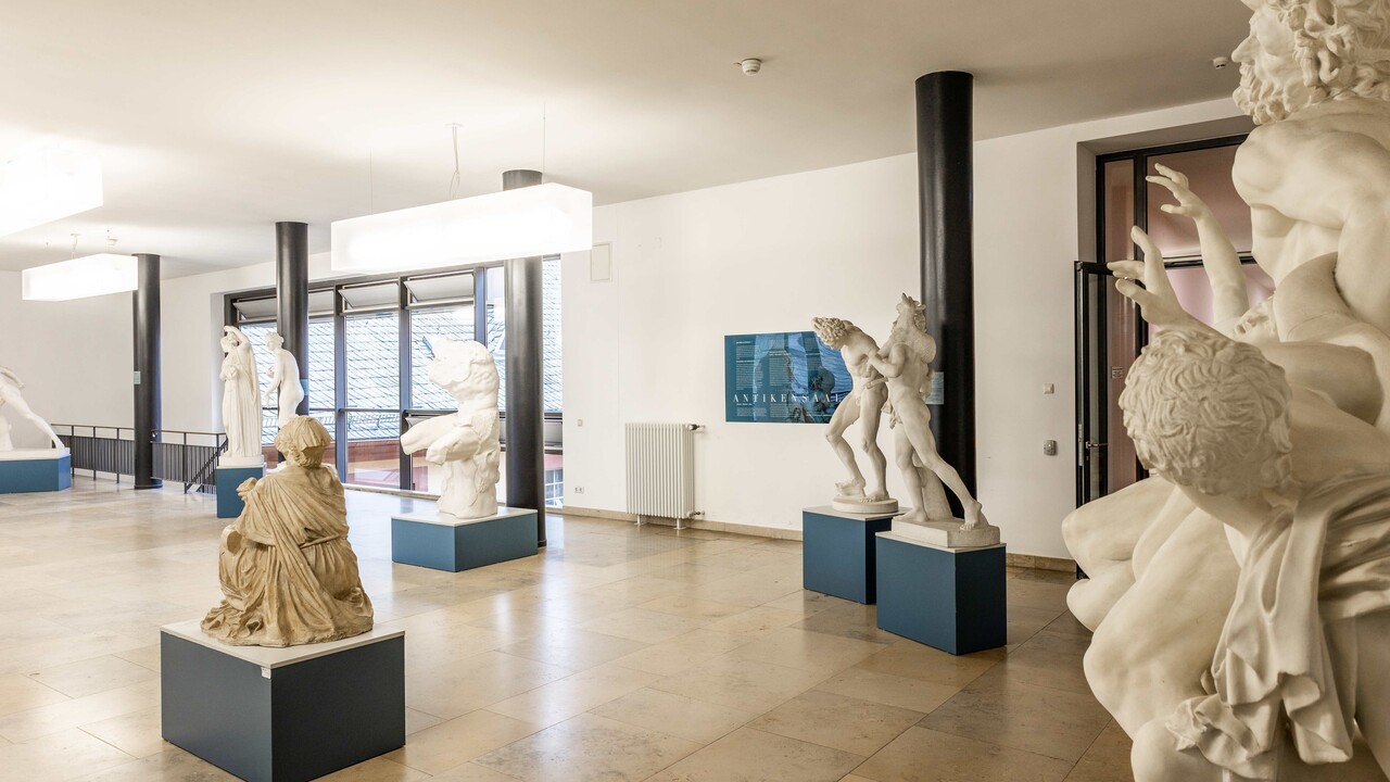 In einem Gang sind antike Skulpturen von Menschen ausgestellt.