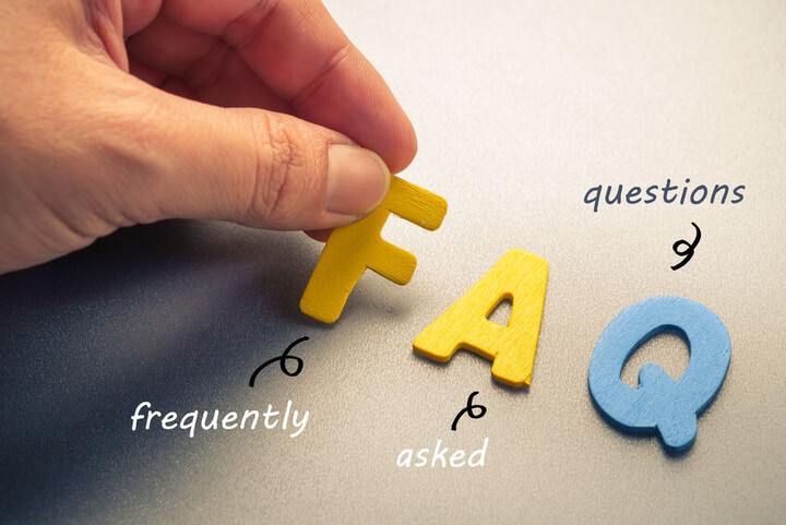 Eine Hand legt mit Buchstaben das Wort FAQ
