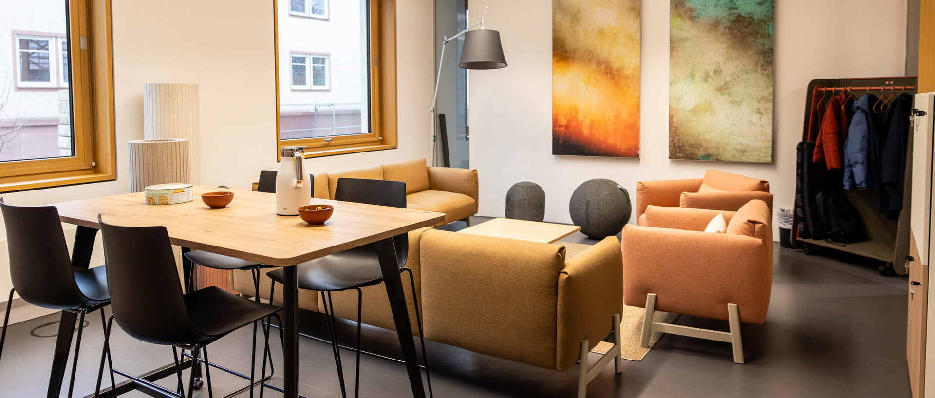 Das Bild zeigt einen CAS-Raum. Darin stehen ein hoher Tisch mit Barhockern und eine Polstergarnitur.