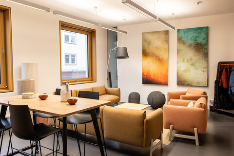 Das Bild zeigt einen hohen Tisch mit Barhockern und eine Sitzgarnitur.