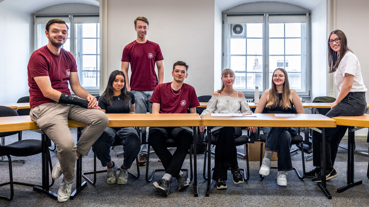 Mitglieder der Mannheim Debating Union sitzen an und auf Tischen.