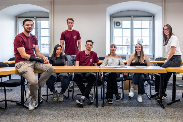 Mitglieder der Mannheim Debating Union sitzen an und auf Tischen.