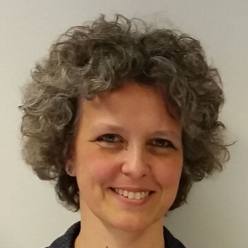 Sandra Eichfelder hat graue lockige Haare. Sie trägt ein dunkelgraues Jacket und eine silberne Halskette.